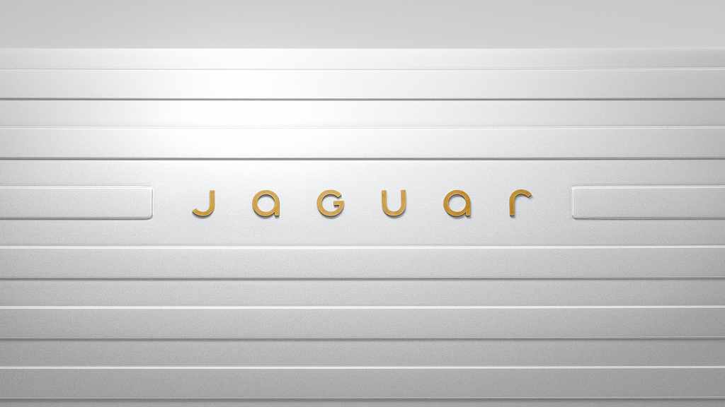 Jaguar wordmark in gold, framed by horizontal lines on a pale metallic surface.