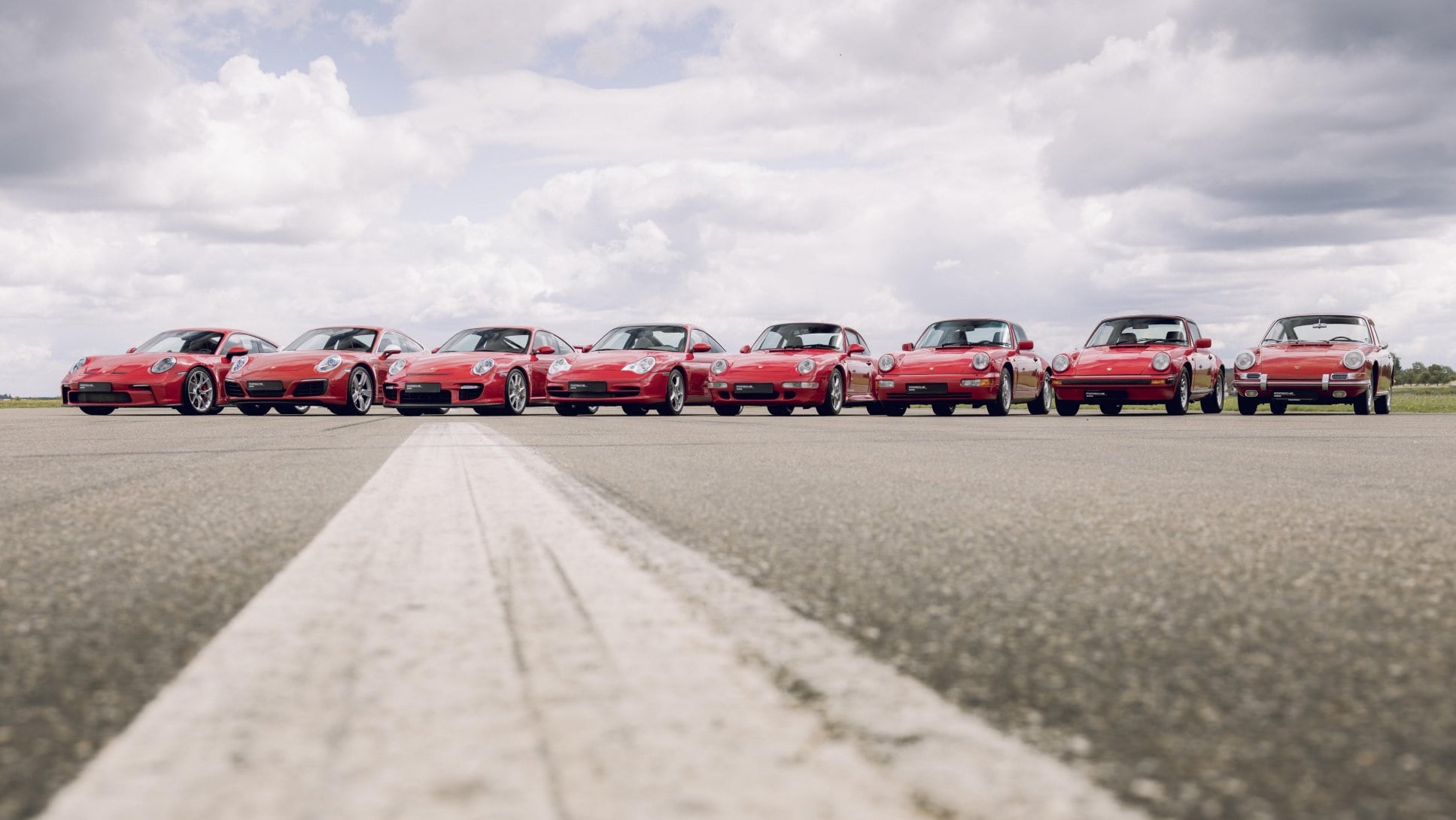 A lineup of red Porsche 911 models from different generations, showing their recognizable shared proportions.