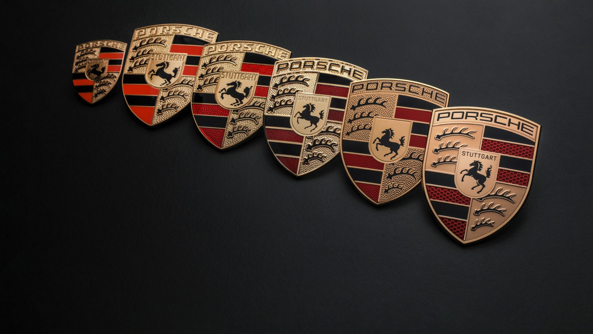 A sequence of Porsche crests showing historical versions and the 2023 design.