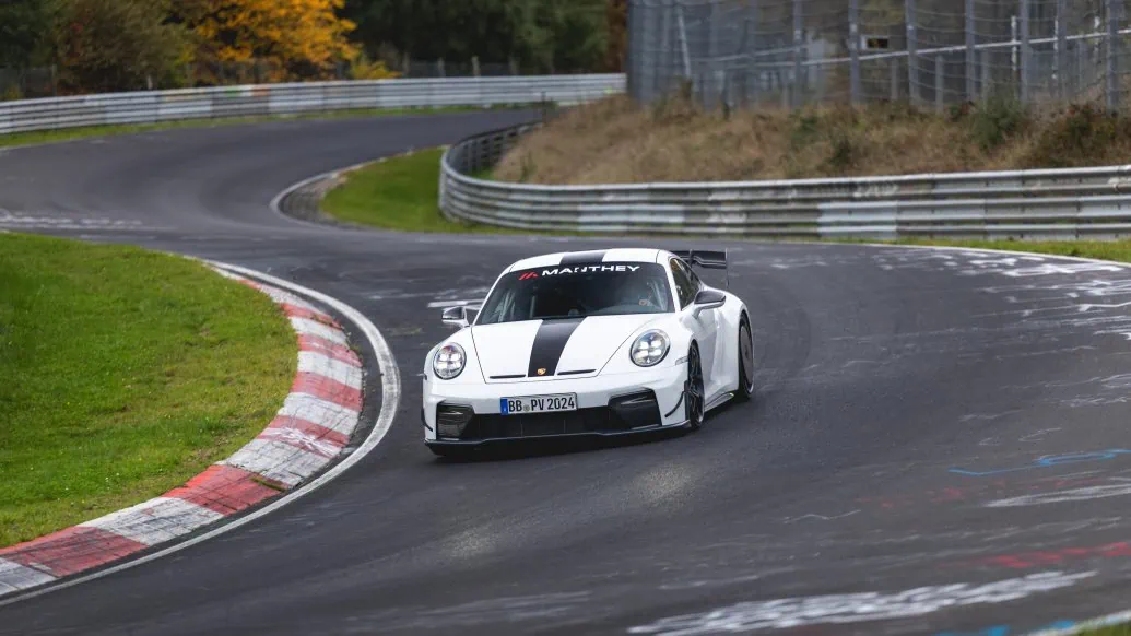 White Porsche 911 GT3 with Manthey Kit driving through a corner at the Nürburgring.