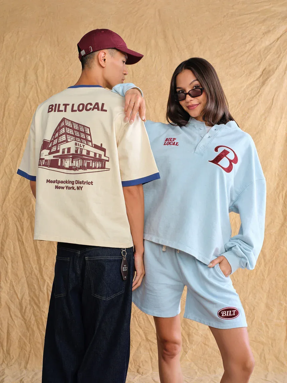Two models wearing Bilt Local apparel, including a cream T-shirt with a Meatpacking District building illustration and a pale blue matching set.