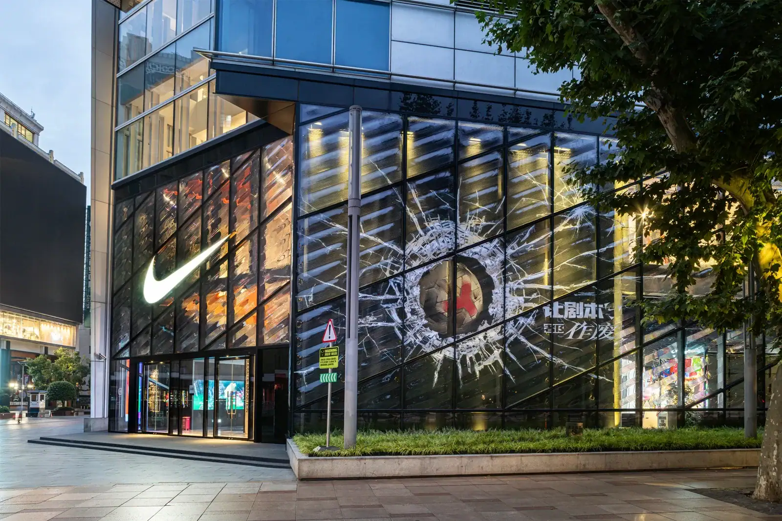 Nike House of Innovation 001 in Shanghai with a football breaking through a glass-effect facade and Chinese campaign lettering
